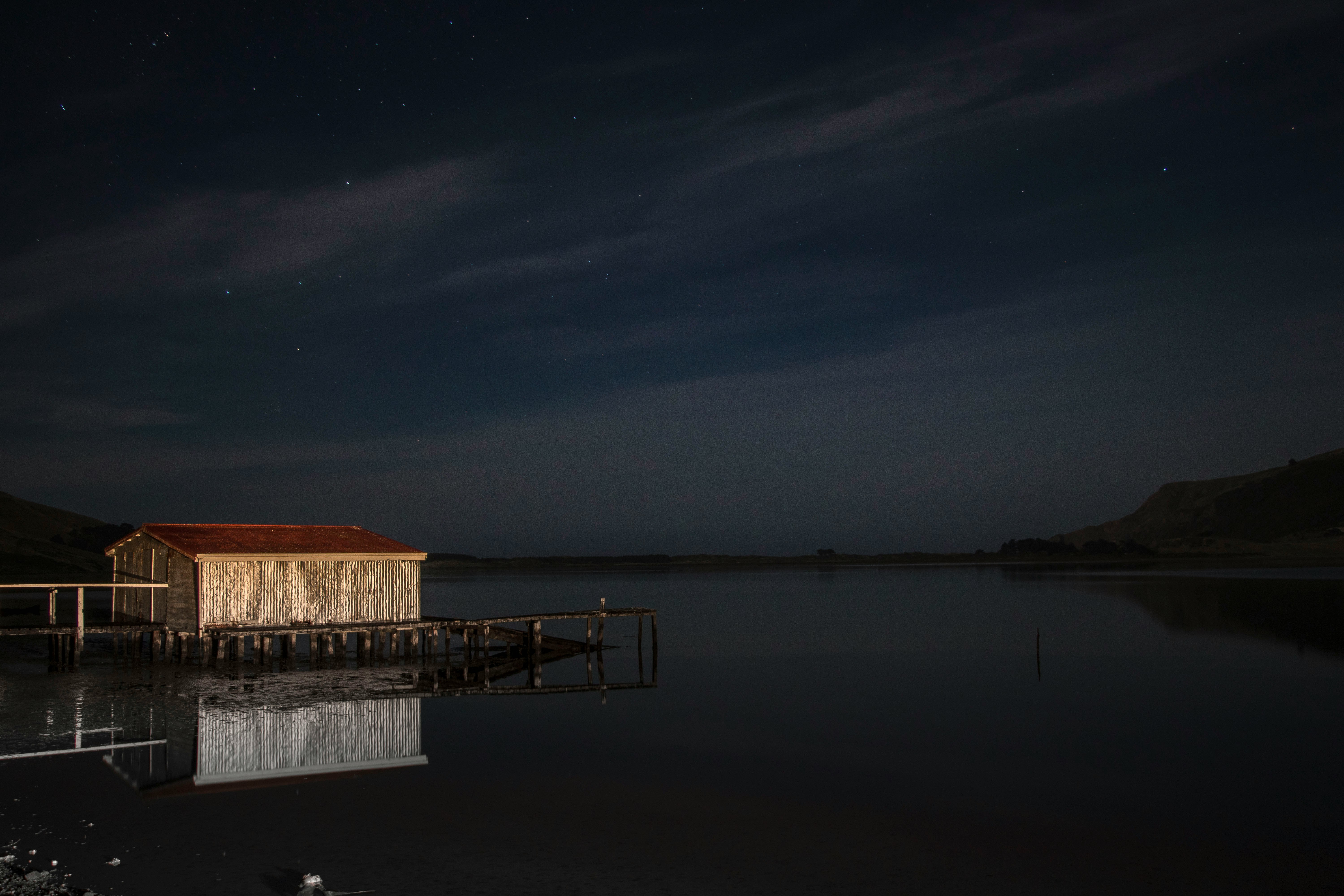 brown and red house near body of water at night illustration